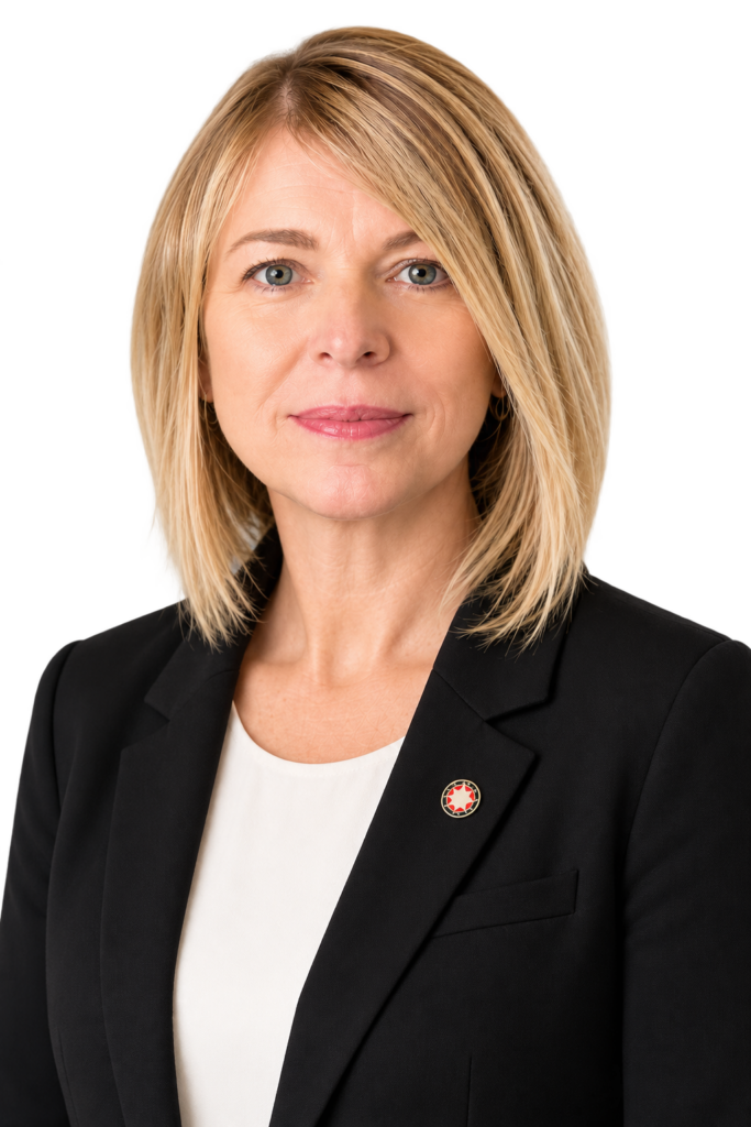 Professional woman in black blazer with Prosperity Now pin, portrait.