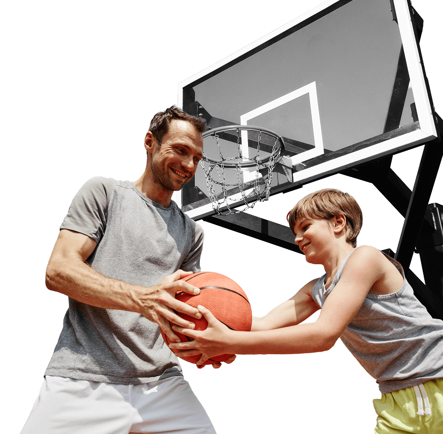 Father and son playing basketball outdoors under a hoop.