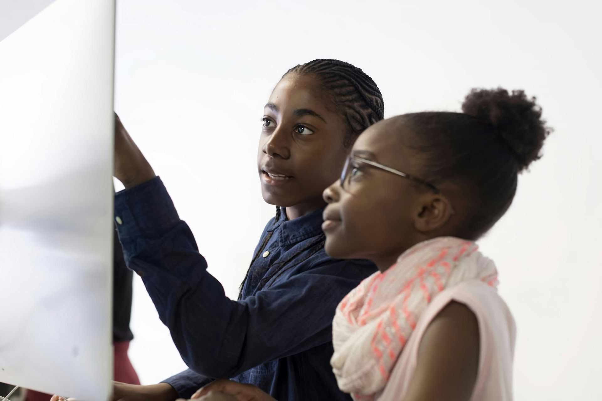 Two young girls engaging with educational content on a whiteboard.